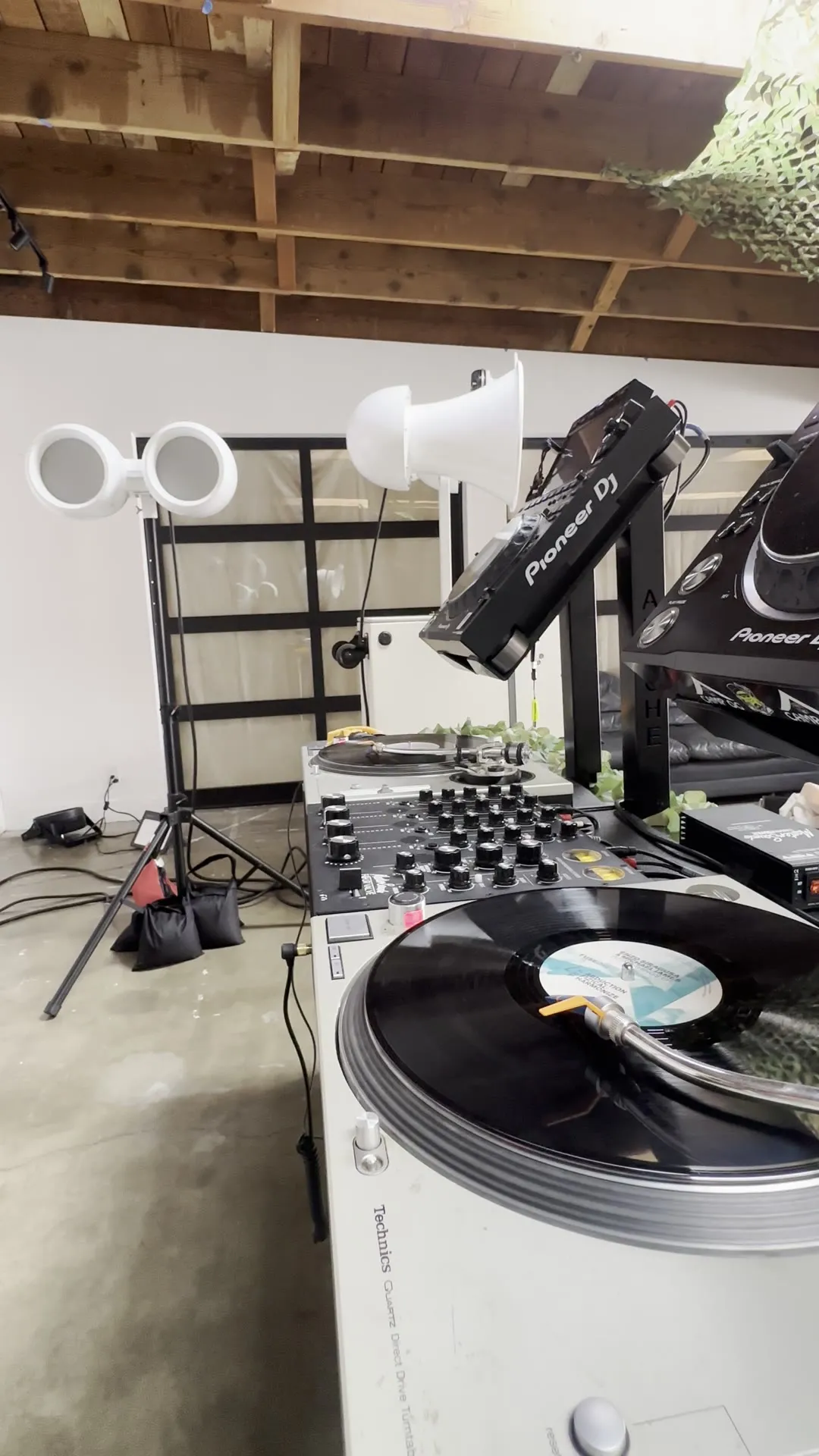 Turntables on a white booth beside Void speakers