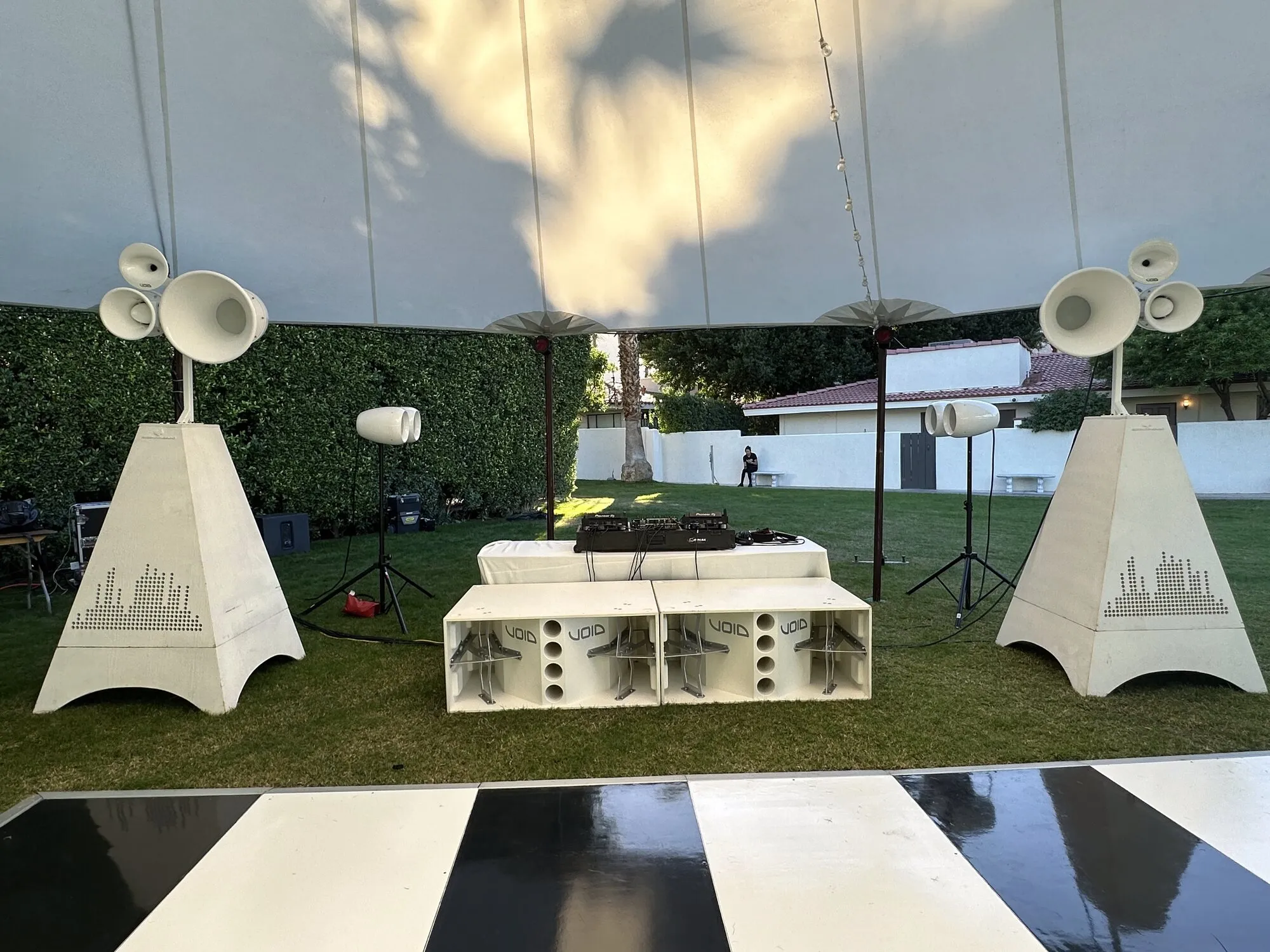 White Void speakers framing a checkerboard dance floor under a wedding tent